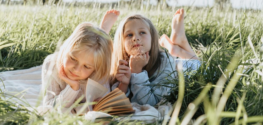Zwei Mädchen liegen im Gras und lesen