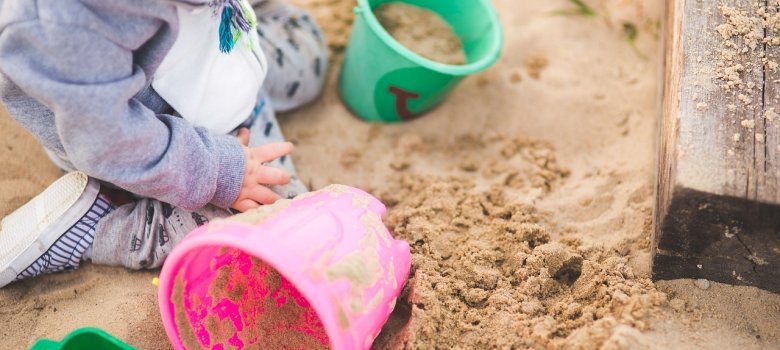 Kind mit Eimern im Sandkasten